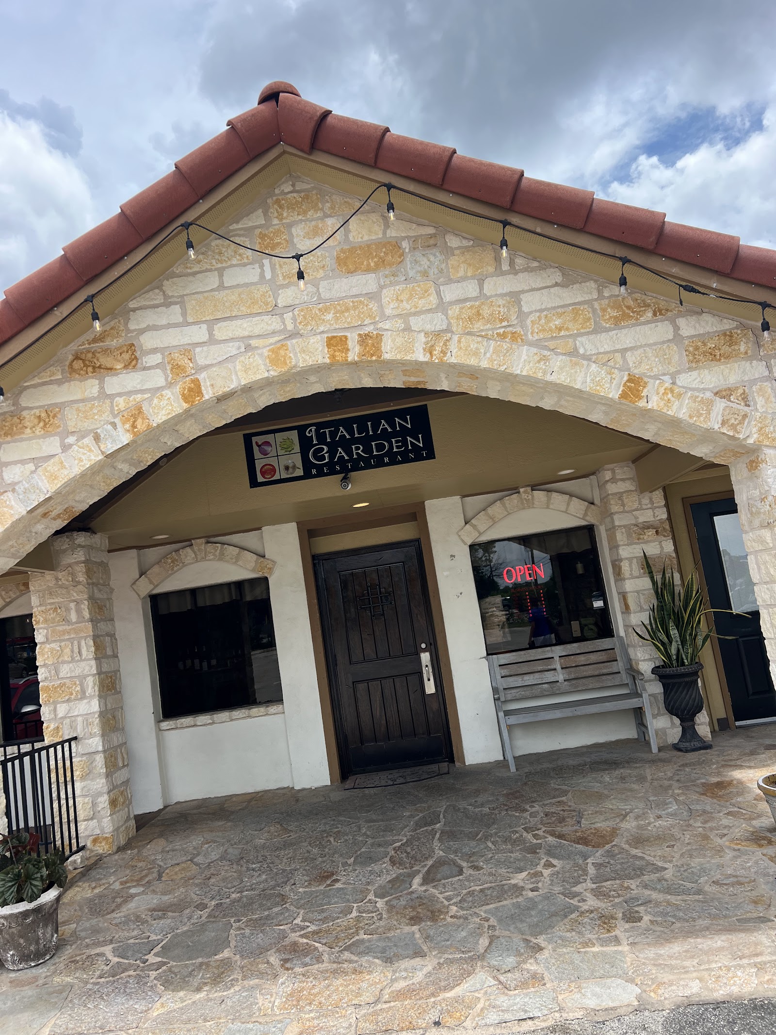 Stone exterior entrance of Italian Garden Cafe under the Hill Country sky