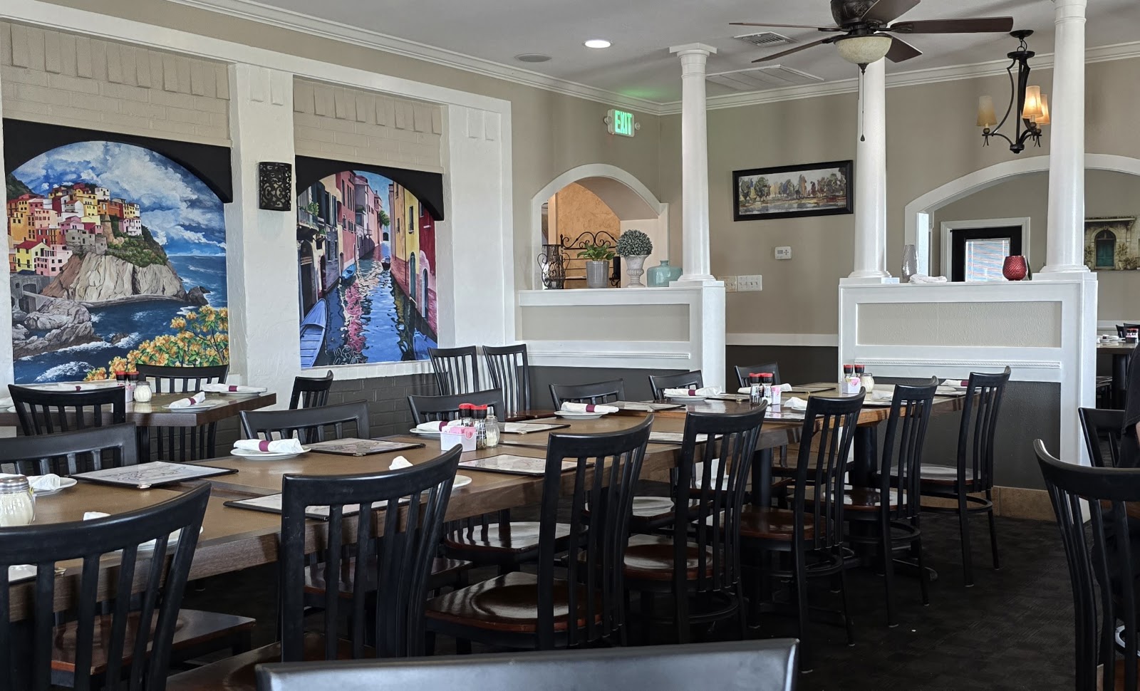 Warm dining room at Italian Garden Cafe with painted murals of Italian coastal villages